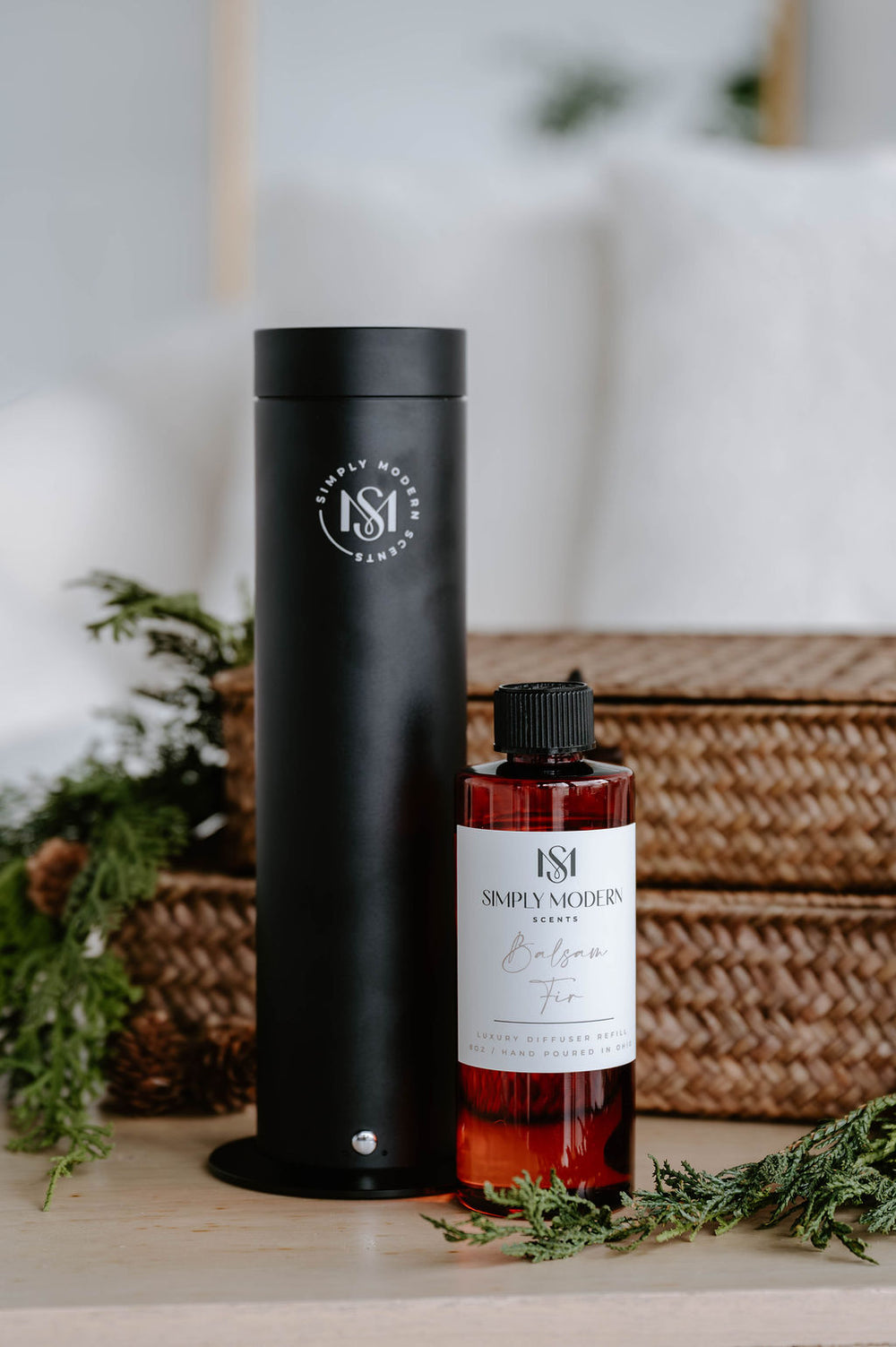 Black electric diffuser beside an 8 oz Balsam Fir luxury diffuser refill with winter greenery