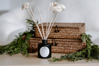 Balsam Fir floral reed diffuser on a wood table with fresh winter greenery