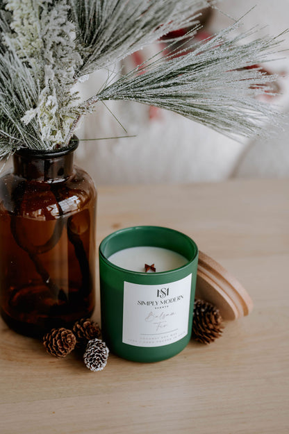 Close view of the Balsam Fir olive candle with its wooden lid and frosted pine and pinecones