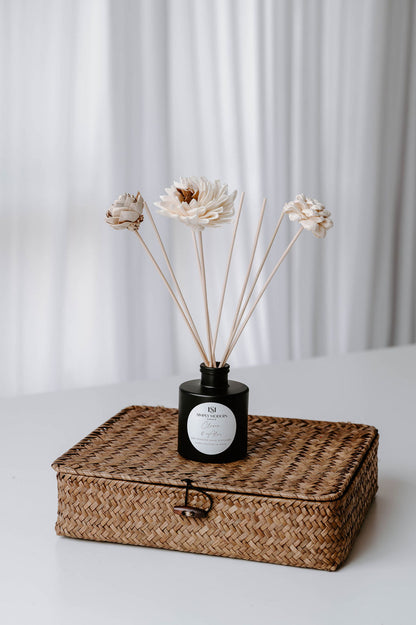 Clover & Aloe floral reed diffuser styled on a woven storage box