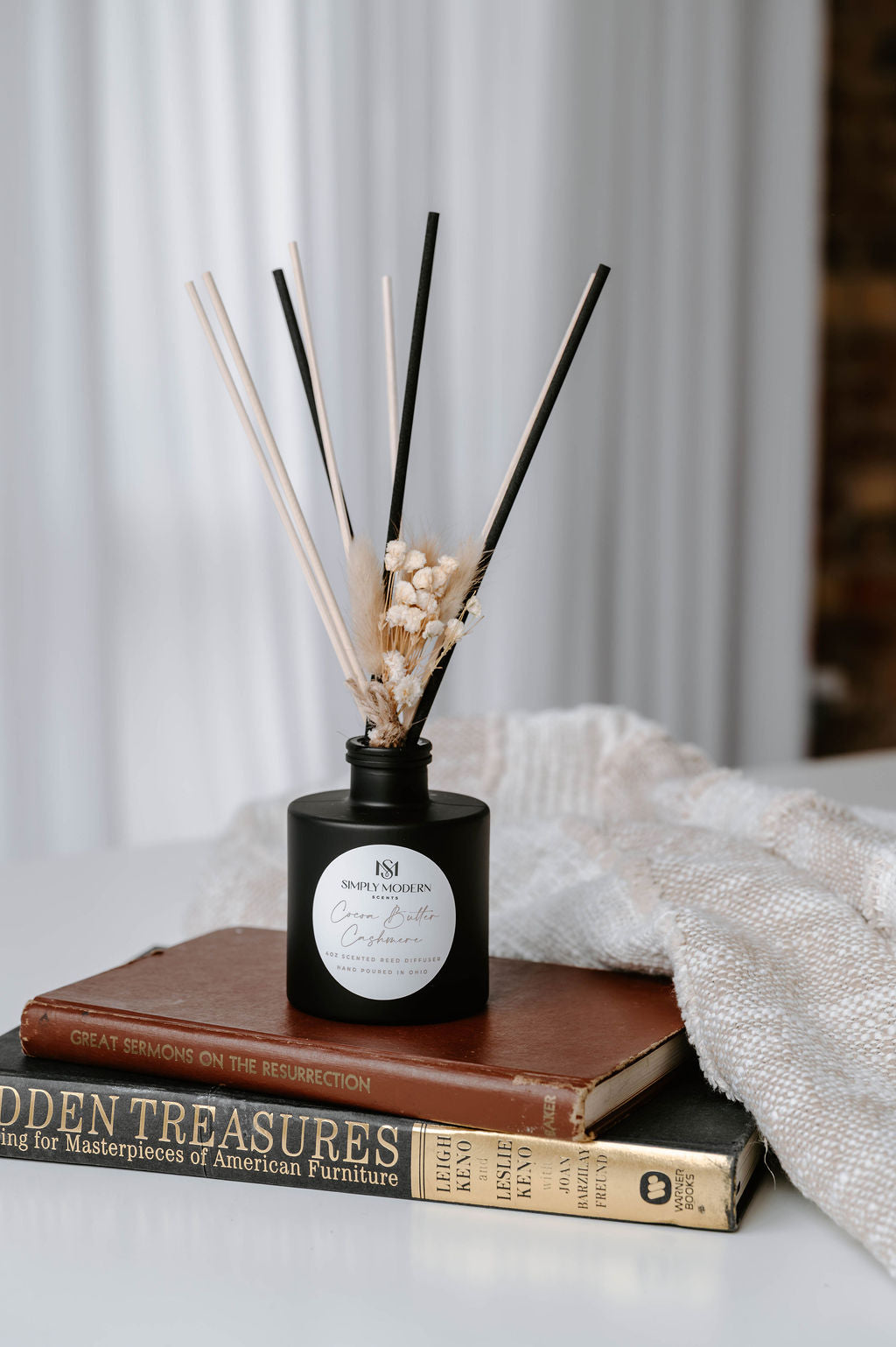 Cocoa Butter Cashmere 4 oz reed diffuser in a matte black bottle with mixed black and natural reeds and dried baby's breath