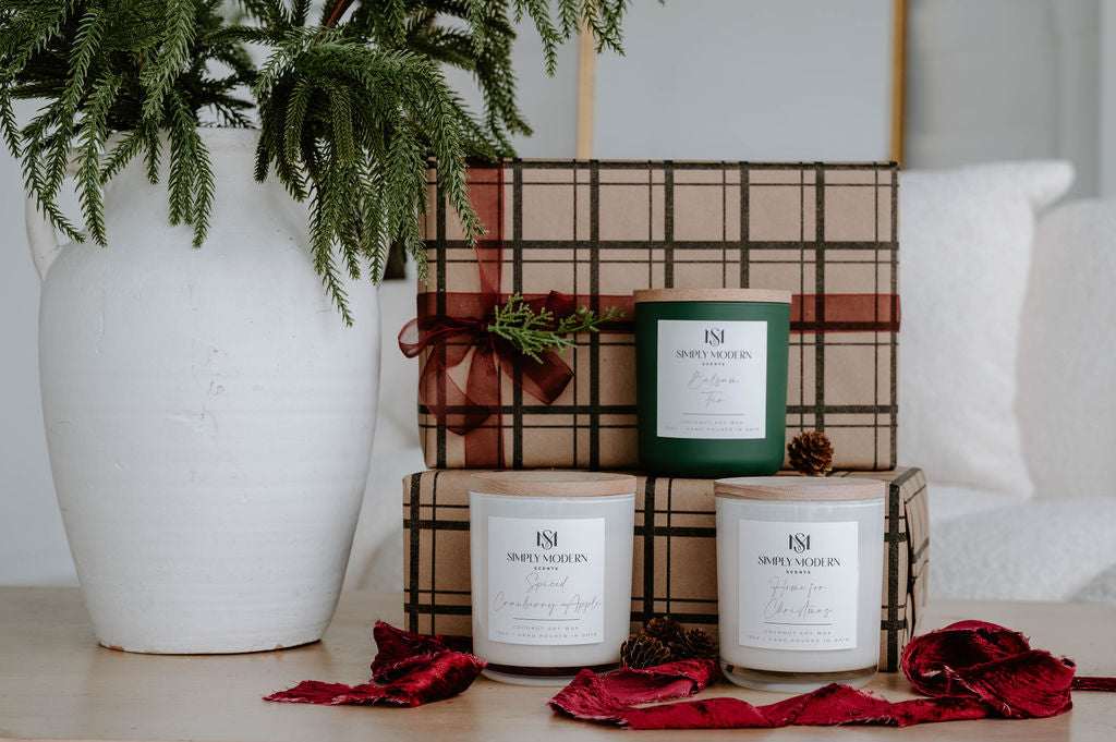 Holiday Candle Trio gift set styled on a wood table with red ribbon and pinecones