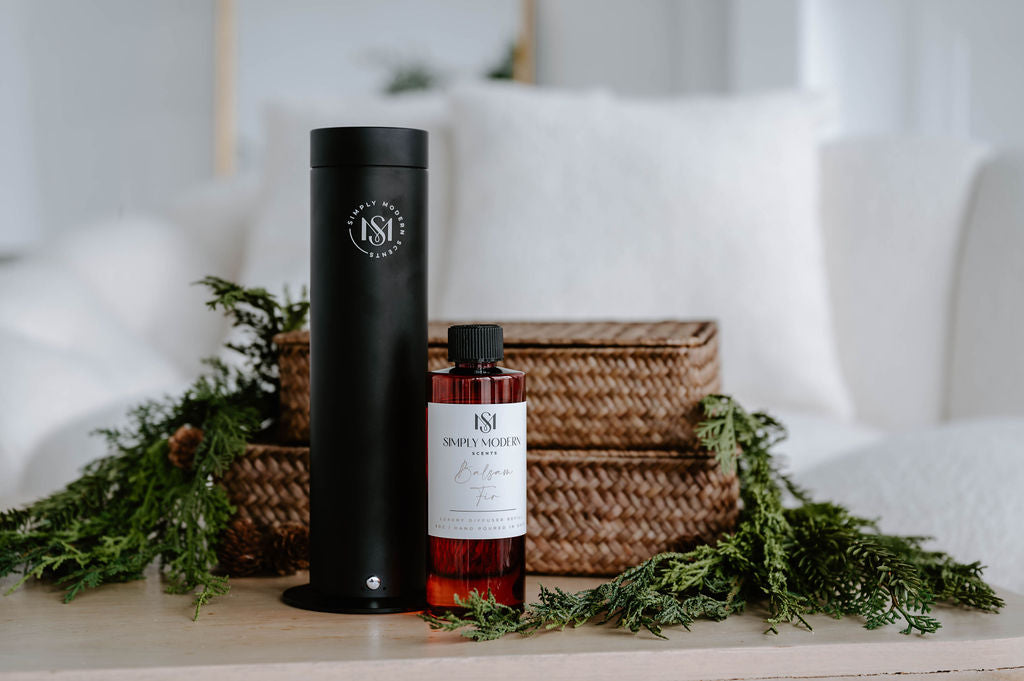 Simply Modern Scents black electric diffuser with Balsam Fir diffuser refill oil, styled with cedar greenery and woven baskets