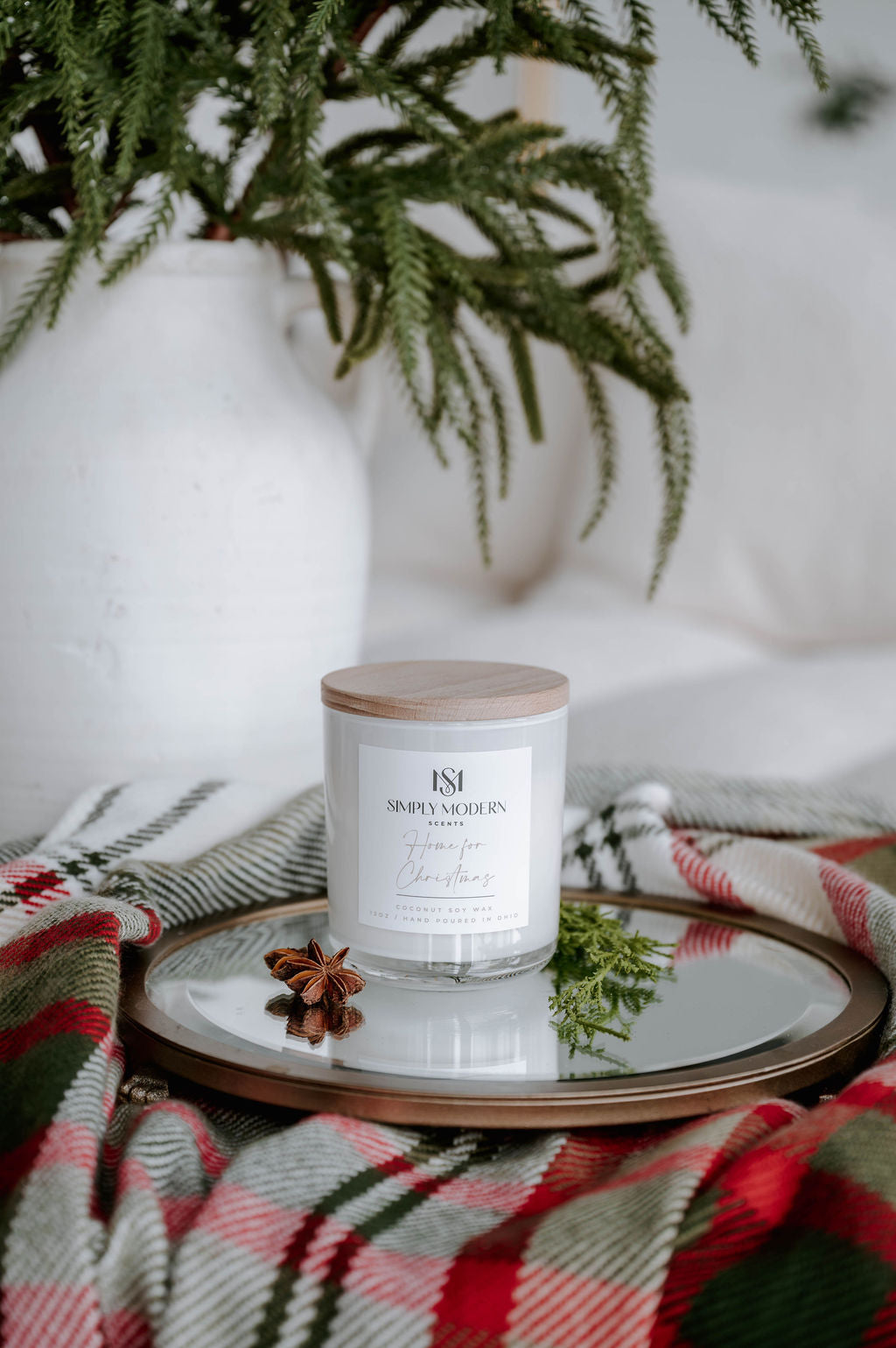 Home for Christmas 12 oz wood-wick coconut soy candle in a white vessel with a wooden lid on a mirrored tray with holiday plaid