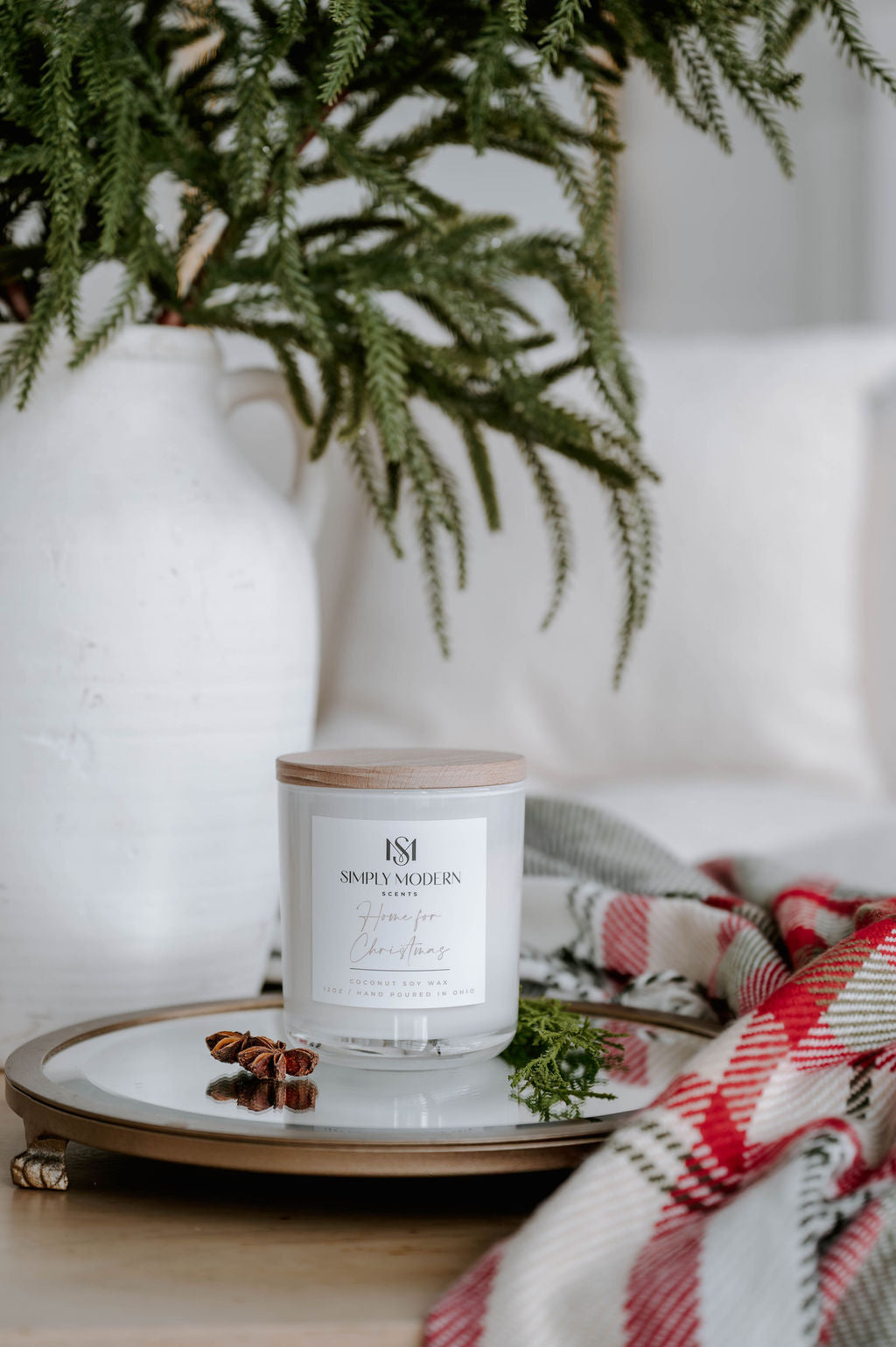 Home for Christmas white 12 oz candle styled with star anise, cedar and a plaid throw