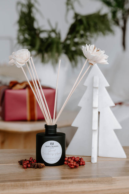 Handmade floral reed diffuser in Spiced Cranberry Apple styled with red berries and a marble tree