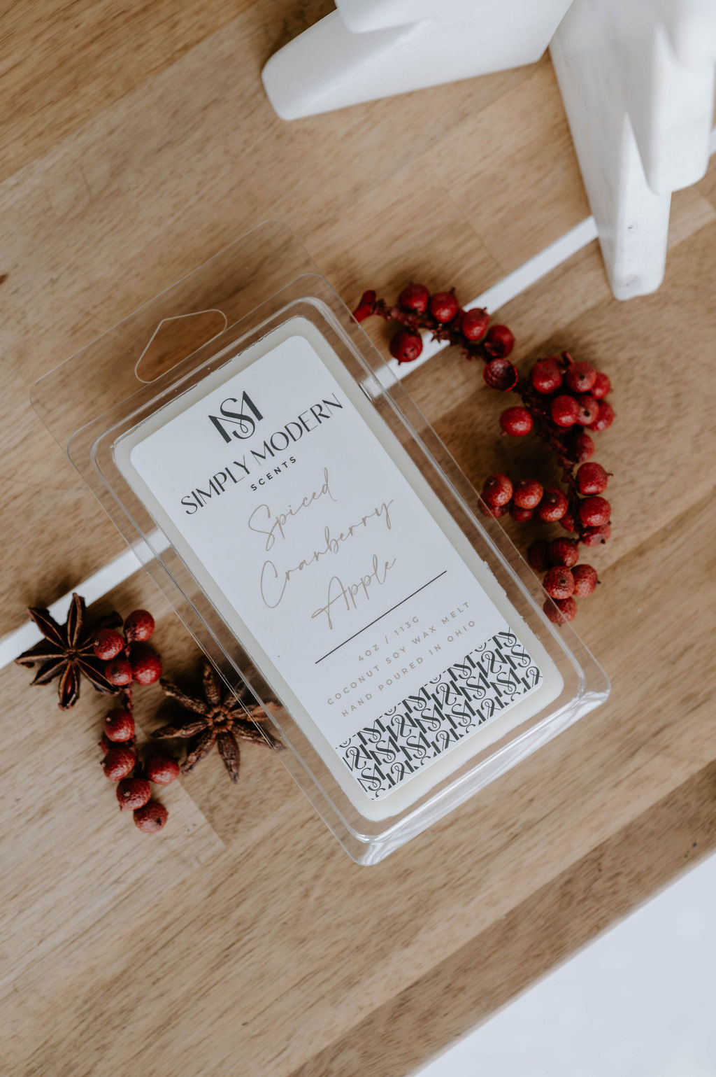 Spiced Cranberry Apple 4 oz coconut soy wax melt clamshell on a wood board with red winter berries and star anise