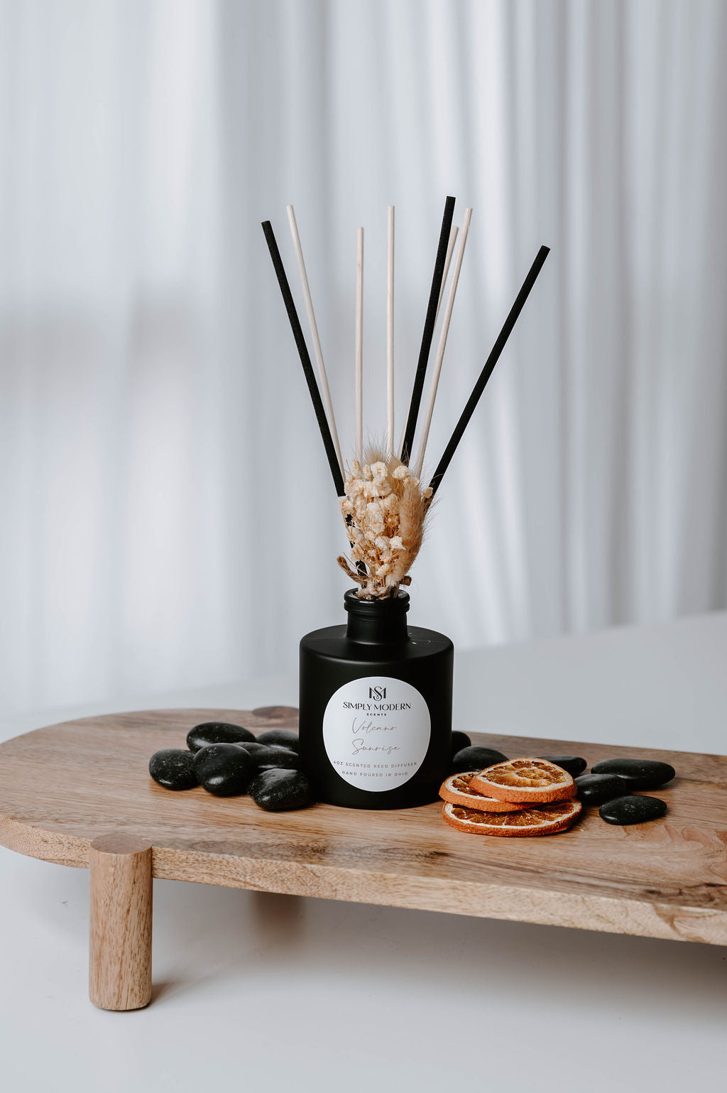 Volcano Sunrise 4 oz reed diffuser in a matte black bottle with mixed reeds, dried baby's breath and dried orange slices