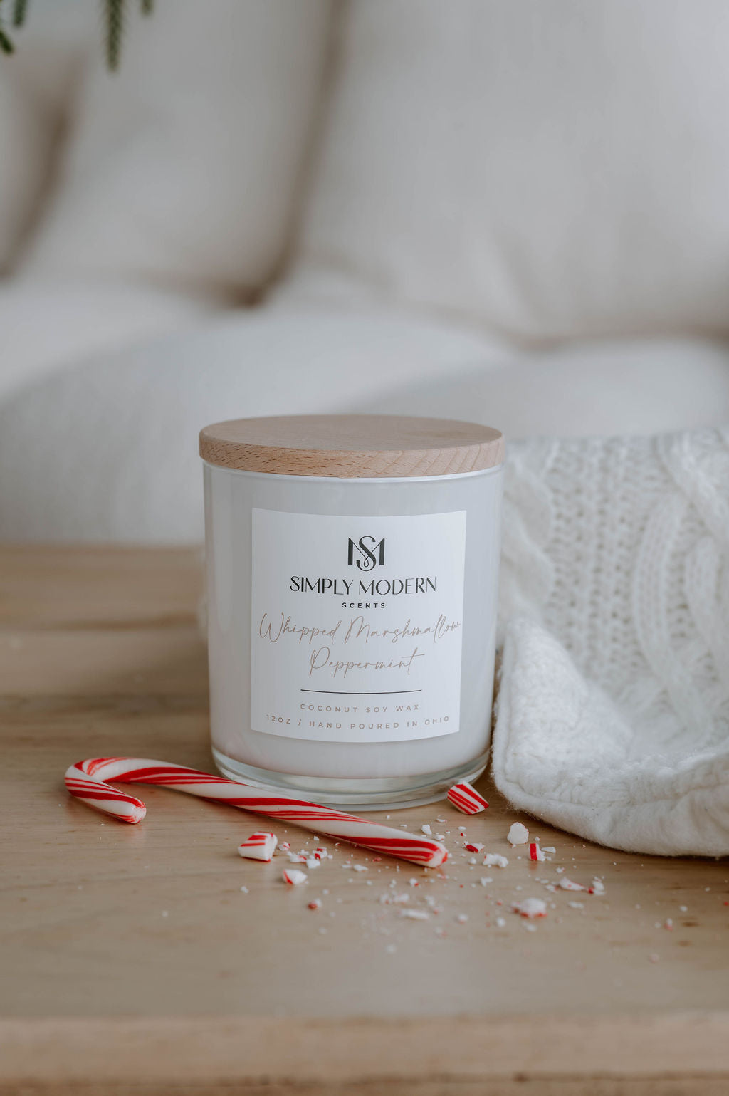 Whipped Marshmallow Peppermint candle on a wood table with a white knit throw and peppermint candy